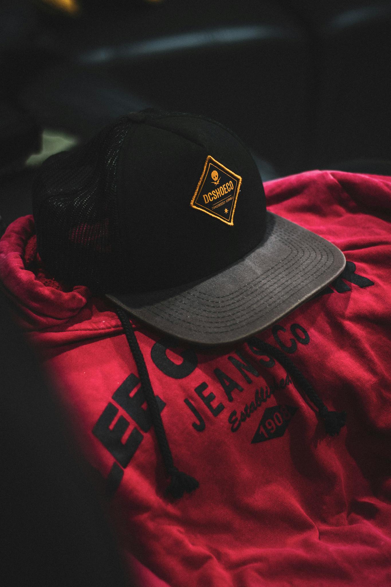 Close-up image of a black cap with logo on a red hoodie, perfect for fashion and streetwear themes.