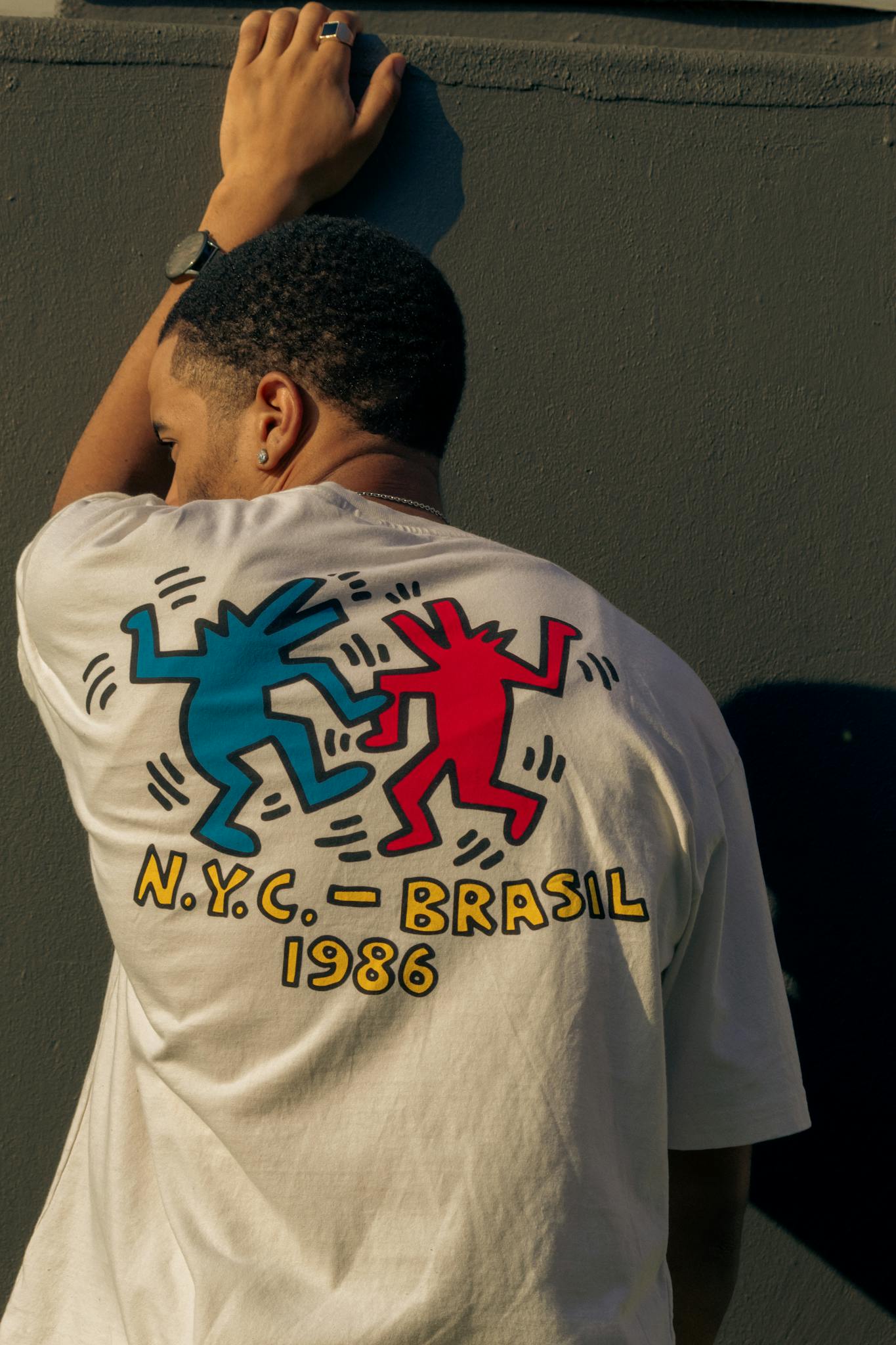 Man wearing a trendy t-shirt with a vibrant NYC - Brasil 1986 print, captured from behind.
